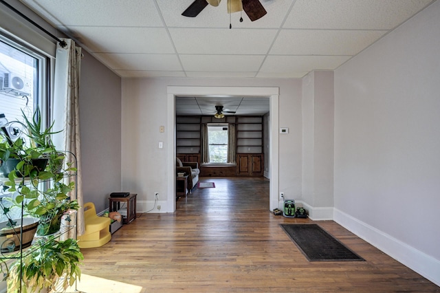 corridor with baseboards, visible vents, a drop ceiling, and wood finished floors