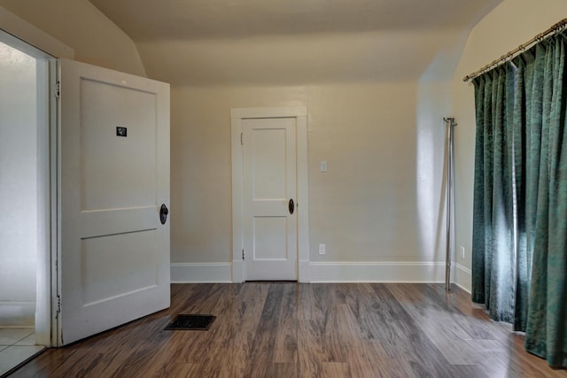 unfurnished room with baseboards, visible vents, vaulted ceiling, and wood finished floors