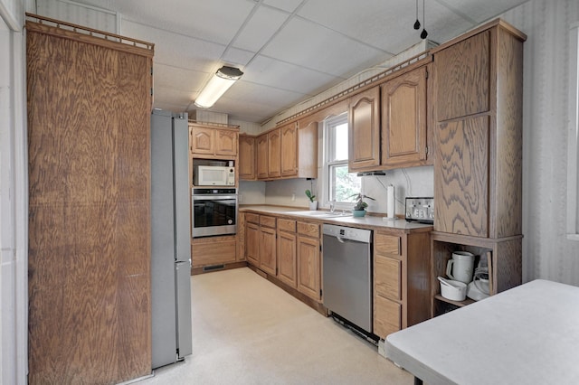 kitchen featuring appliances with stainless steel finishes, a paneled ceiling, light countertops, and a sink