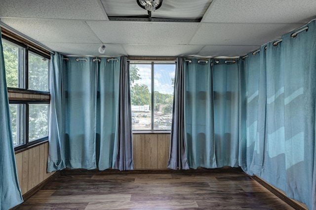 spare room featuring wood walls, wood finished floors, and a paneled ceiling