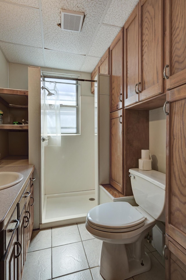 full bath with a drop ceiling, toilet, vanity, visible vents, and a shower stall