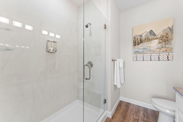 full bathroom featuring wood finished floors, a shower stall, vanity, and baseboards