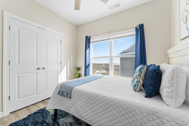 bedroom with light wood-style floors, visible vents, and ceiling fan