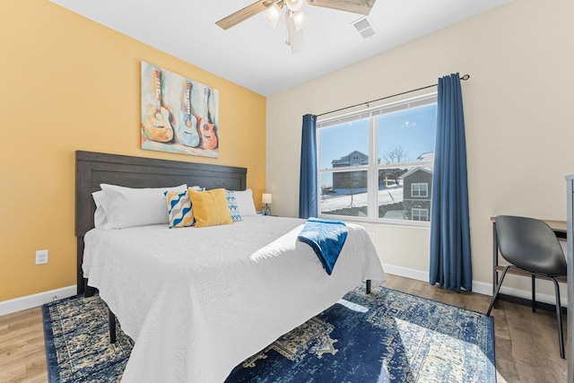 bedroom featuring visible vents, ceiling fan, baseboards, and wood finished floors