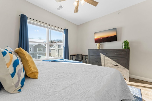 bedroom featuring a ceiling fan, wood finished floors, visible vents, and baseboards