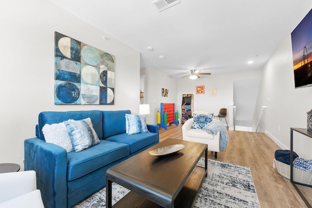 living area with light wood-style flooring, a ceiling fan, visible vents, and baseboards