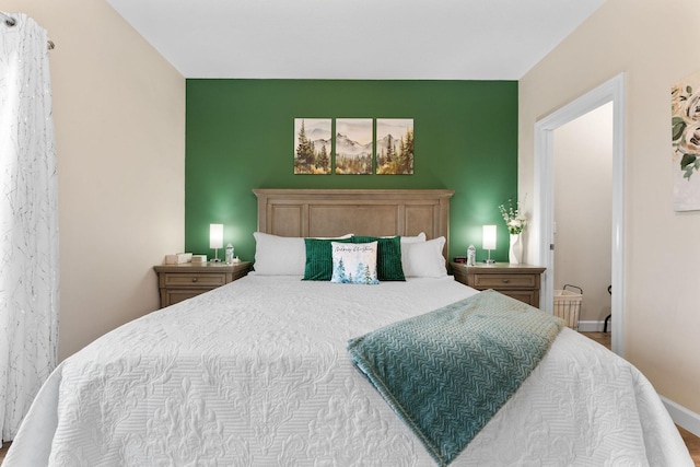 bedroom with an accent wall and baseboards