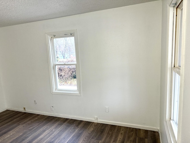 empty room featuring a textured ceiling, baseboards, and dark wood-type flooring