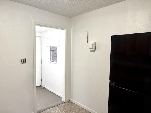 hall featuring a textured ceiling and baseboards