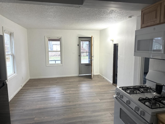 kitchen with a textured ceiling, baseboards, range with gas stovetop, and wood finished floors