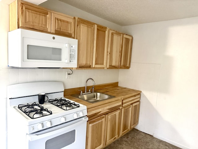 kitchen featuring white appliances, a textured ceiling, and a sink