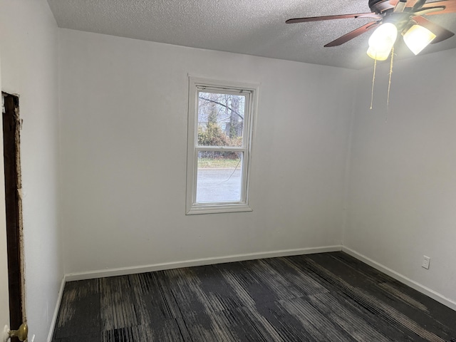 unfurnished room featuring a textured ceiling, ceiling fan, dark wood finished floors, and baseboards