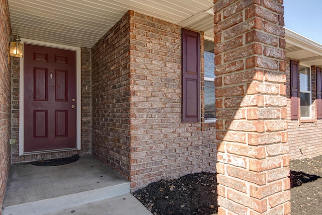 property entrance featuring covered porch and brick siding