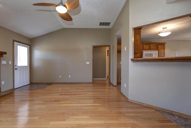 unfurnished living room featuring visible vents, lofted ceiling, ceiling fan, a textured ceiling, and light wood-type flooring