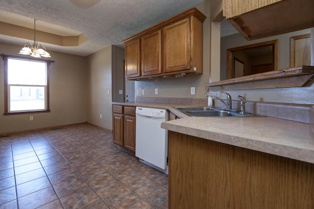 kitchen featuring a textured ceiling, a sink, dishwasher, brown cabinetry, and a raised ceiling