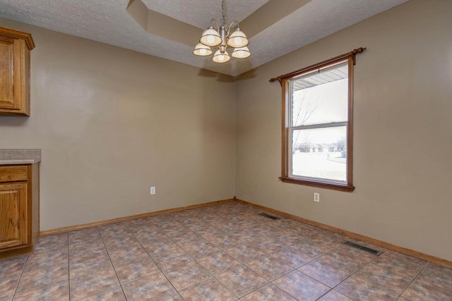 unfurnished dining area featuring a chandelier, visible vents, a textured ceiling, and baseboards