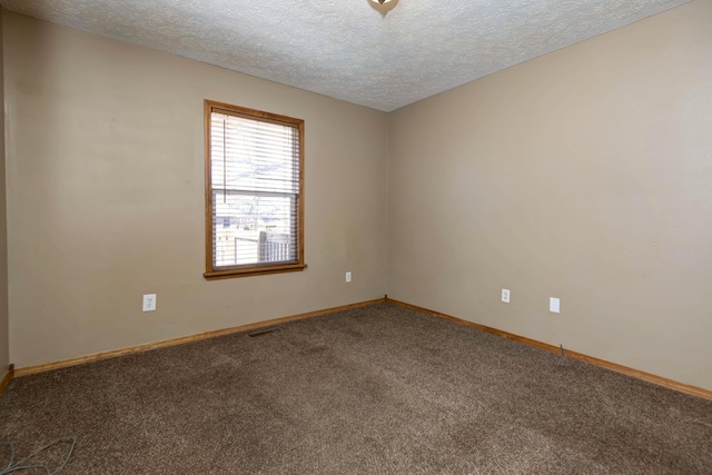 spare room with a textured ceiling, carpet flooring, visible vents, and baseboards