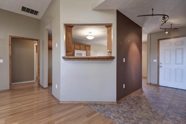 kitchen featuring white microwave, visible vents, and a textured ceiling