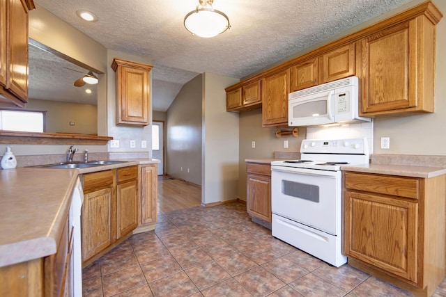 kitchen featuring white appliances, brown cabinets, a sink, and light tile patterned flooring