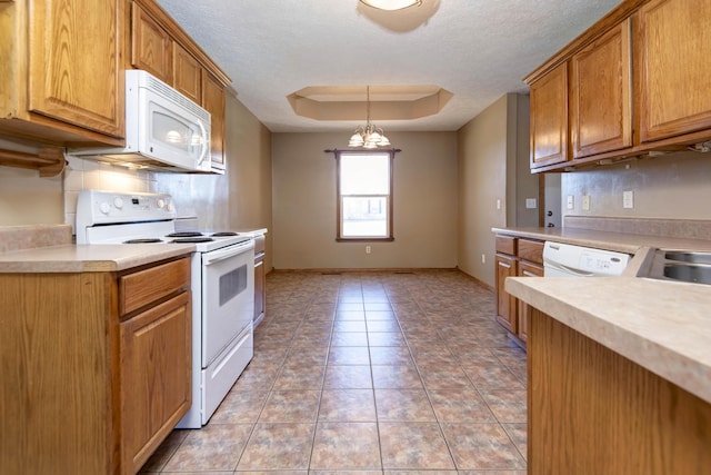 kitchen with light countertops, white appliances, light tile patterned flooring, and a raised ceiling