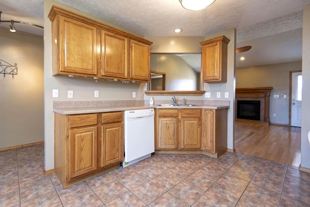 kitchen with brown cabinetry, white dishwasher, light countertops, and a sink