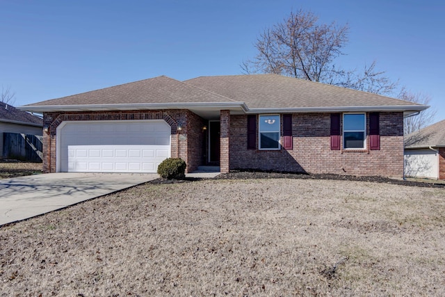 ranch-style house with a garage, driveway, brick siding, and roof with shingles