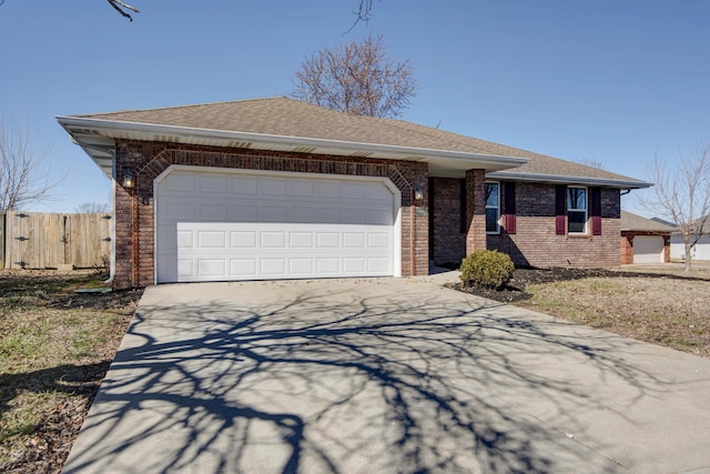 ranch-style home featuring a garage, brick siding, fence, driveway, and roof with shingles