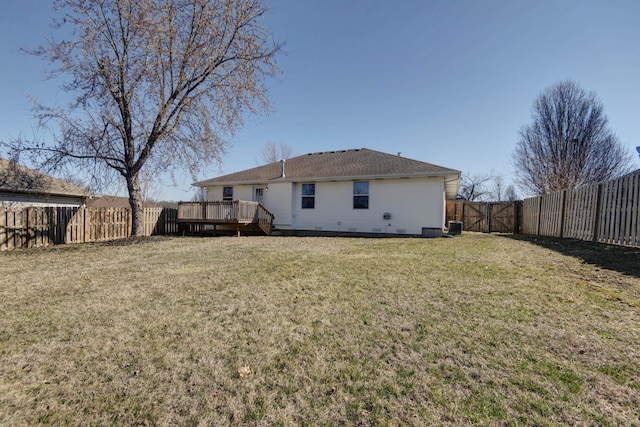 rear view of property featuring a fenced backyard, a deck, and a lawn