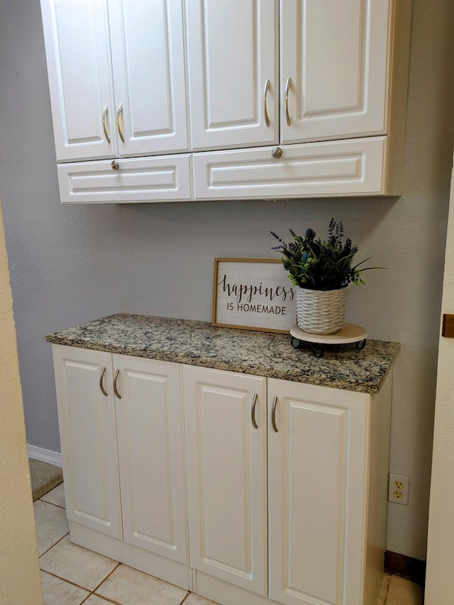 interior space with stone counters, white cabinets, baseboards, and light tile patterned floors