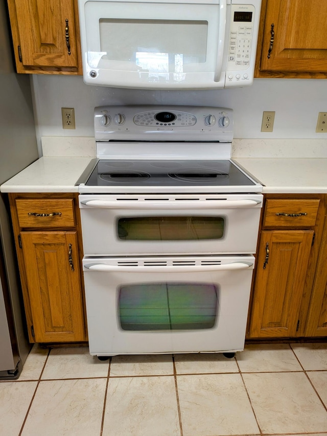 kitchen with light countertops, white appliances, brown cabinets, and light tile patterned flooring