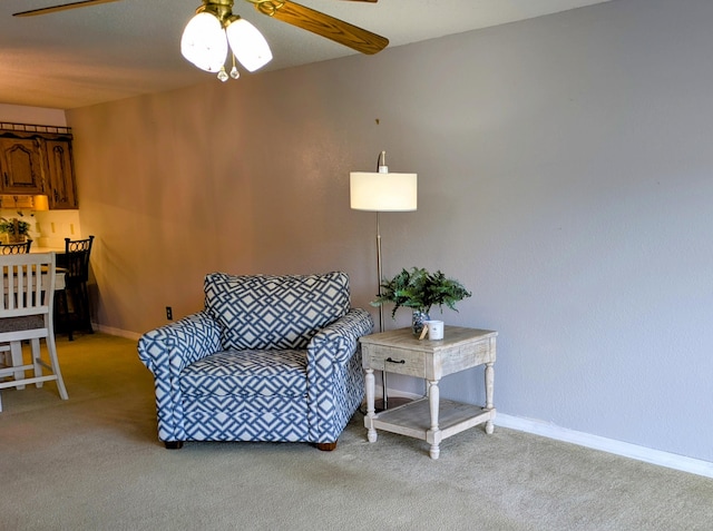 living area with baseboards, a ceiling fan, and light colored carpet