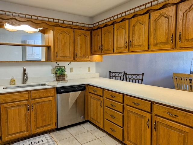 kitchen featuring light tile patterned floors, light countertops, stainless steel dishwasher, brown cabinetry, and a sink