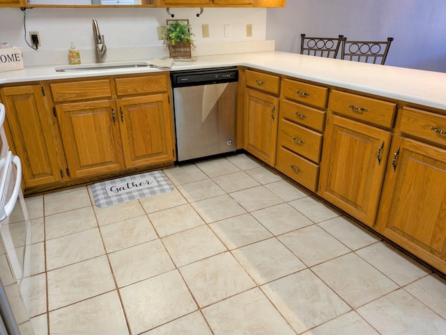 kitchen featuring brown cabinets, light tile patterned flooring, dishwasher, and a sink