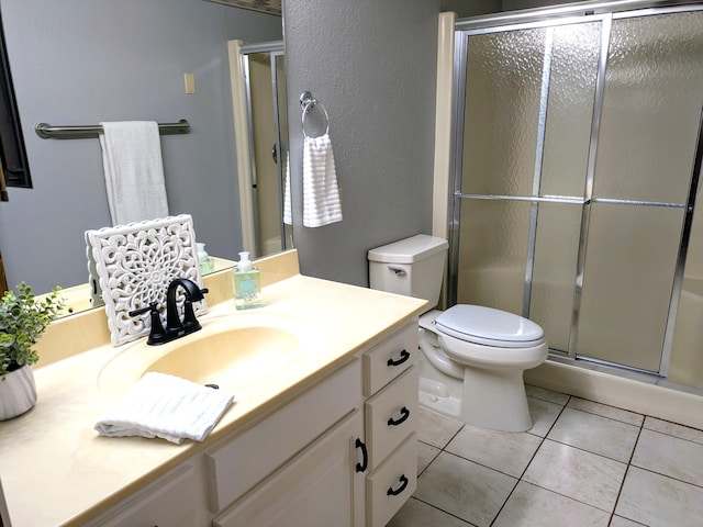 bathroom with toilet, a shower stall, vanity, and tile patterned floors