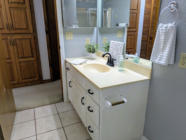 bathroom with a textured wall, vanity, and tile patterned floors