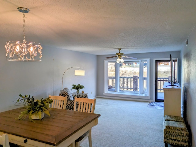 carpeted dining area featuring a textured ceiling and ceiling fan with notable chandelier