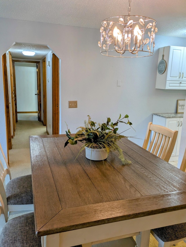 unfurnished dining area featuring a textured ceiling, arched walkways, and light colored carpet