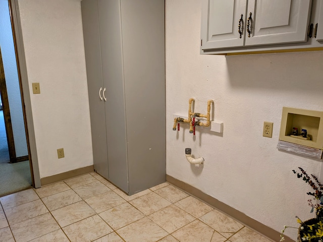 clothes washing area featuring cabinet space, baseboards, gas dryer hookup, washer hookup, and light tile patterned flooring