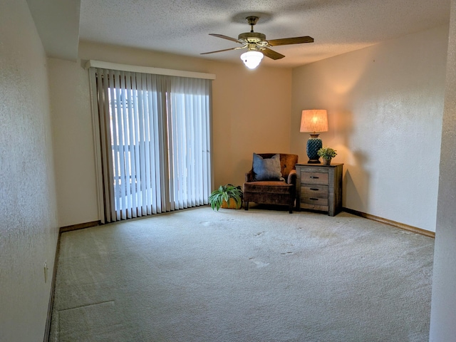 living area with carpet floors, a textured wall, a textured ceiling, and baseboards