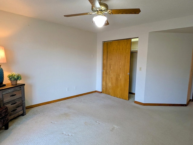 unfurnished bedroom featuring a ceiling fan, a closet, carpet flooring, and baseboards