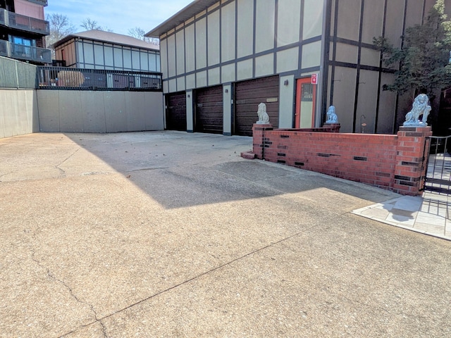 garage with concrete driveway and fence