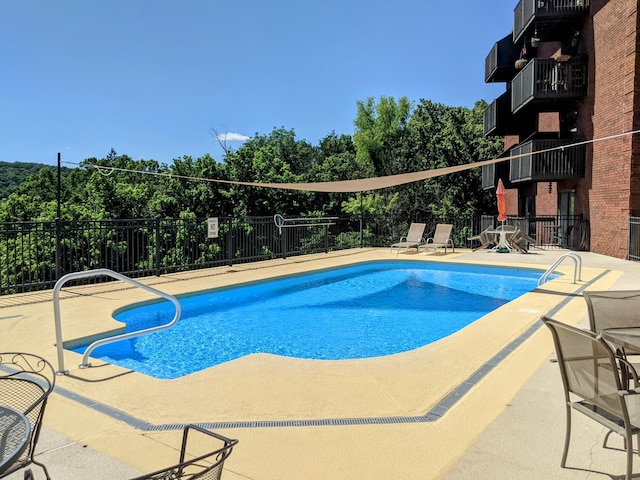 community pool with a patio and fence