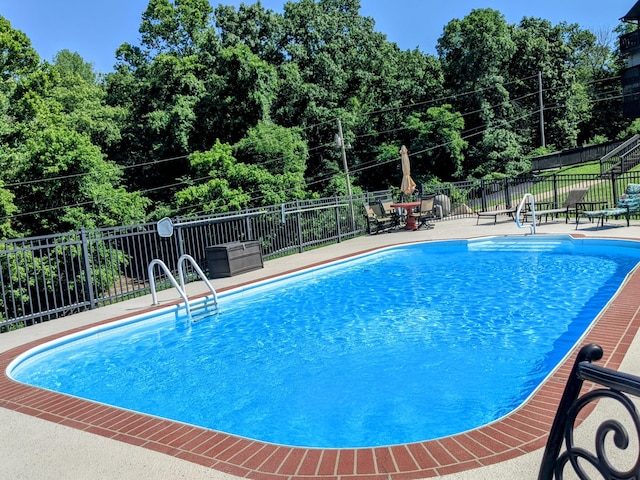 community pool with a patio area and fence