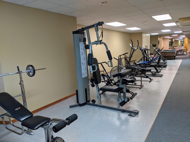 workout area with a drop ceiling, visible vents, and baseboards