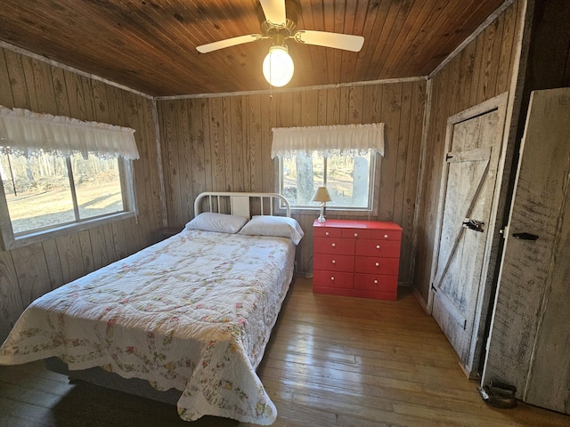 bedroom featuring hardwood / wood-style floors, multiple windows, wood ceiling, and wooden walls