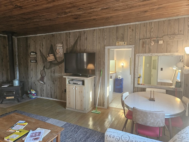 unfurnished living room with wood ceiling, a wood stove, wood walls, and hardwood / wood-style floors