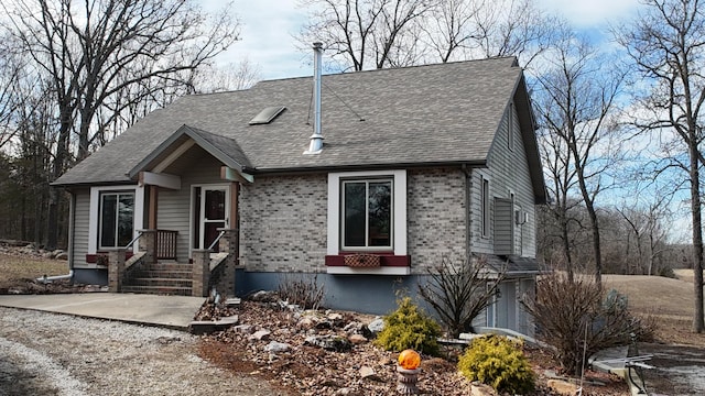 view of front facade with brick siding and a shingled roof