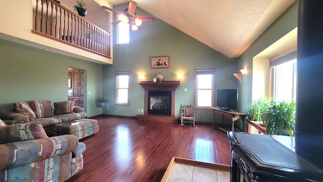 living area with a fireplace with raised hearth, wood finished floors, a wealth of natural light, and baseboards