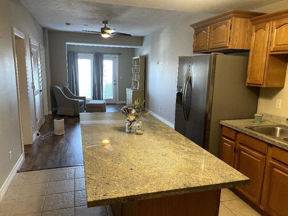 kitchen featuring a center island, baseboards, a sink, and stainless steel fridge with ice dispenser