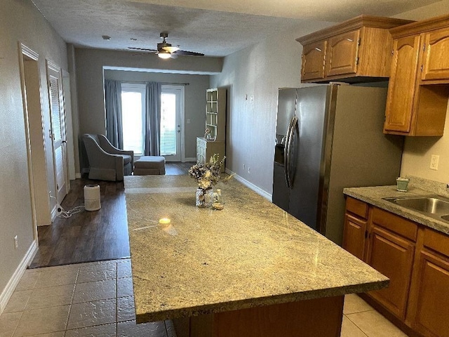 kitchen featuring a center island, baseboards, a sink, and stainless steel fridge with ice dispenser